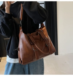Brown retro large capacity tote bag with dual handles and adjustable shoulder strap worn by model
