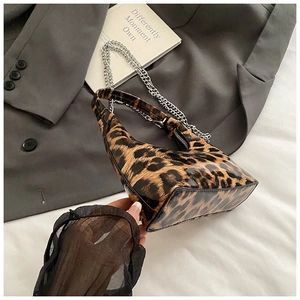 Detail of glossy leopard print hobo bag with silver chain strap on a gray blazer