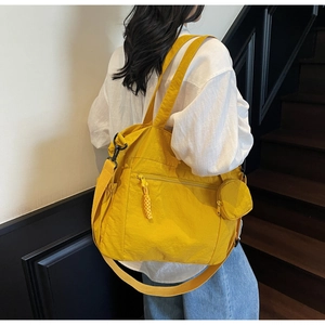 Detail of yellow nylon tote bag with wide straps and round coin purse hanging on the side