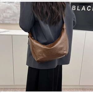 Brown vintage hobo bag with knotted shoulder strap worn on person in indoor setting