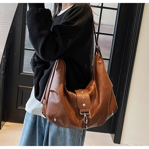 Detail of vintage brown leather tote bag showing star rivets and metallic buckle accents