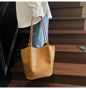 Καφέ τσάντα tote με υφή κροκόδειλου φορεμένη από μοντέλο σε μια σκάλα