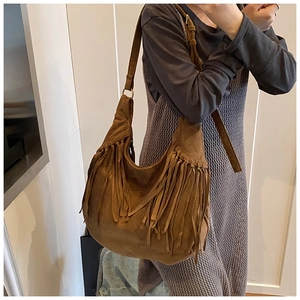 Brown faux suede hobo bag with fringe details shown on model in a casual setting