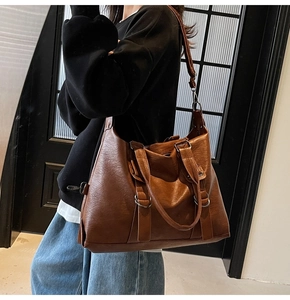 Detail of vintage brown faux leather tote bag with metallic hardware and textured finish
