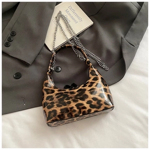 Detail of glossy leopard print hobo bag with a sleek silver chain strap on a suit