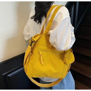 Detail of a yellow nylon tote bag with adjustable shoulder strap and small coin purse
