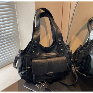 Close-up of black vintage texture faux leather handbag with metal buckle and shoulder strap
