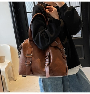 Detail of dark brown faux leather tote showing soft texture and silver buckle accents