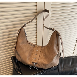 Close-up of vintage brown leather hobo bag featuring silver star studs and metal buckle detail