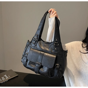 Detail of black pebbled leather texture and buckle pocket on large tote bag