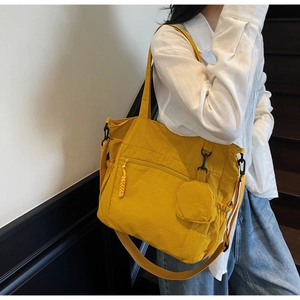 Detail of a bright yellow nylon tote bag with front zipper pocket and a small round pouch