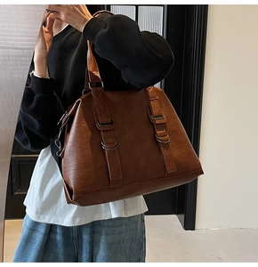 Detail of a brown vintage tote bag featuring textured leather and metal D-ring buckles
