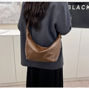 Brown retro leather crescent bag shown worn by a model in a stylish interior setting