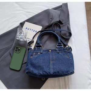 Vista piatta di borsa tote in denim con rivetti metallici e tracolla con accessori vita