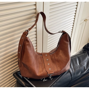 Close-up of brown textured leather hobo bag featuring silver star studs and eyelets