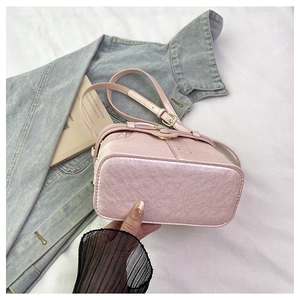 Close-up of pink litchi grain leather bucket bag base and adjustable gold strap