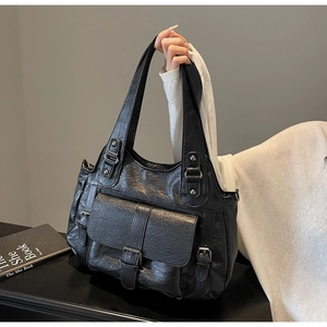 Detail of soft black PU leather tote bag with vintage buckle pocket and double handles