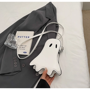 Petit sac bandoulière fantôme blanc minimaliste posé sur un blazer gris et des draps
