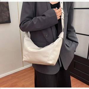 Detail of creamy white crescent bag with wrinkled leather texture and adjustable strap