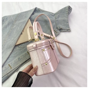 Detail of a pink cylindrical leather crossbody bag with pearly metallic finish and gold studs