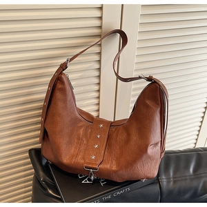 Detail of vintage brown leather tote bag featuring star rivets and silver buckles
