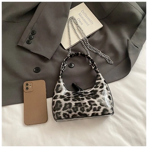Detail of glossy patent leather leopard print handbag with silver chain and crescent shape