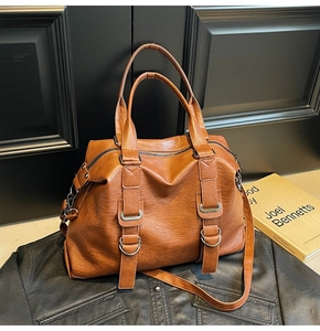 Detailed close-up of brown PU leather Boston bag with metallic D-rings and crossbody strap