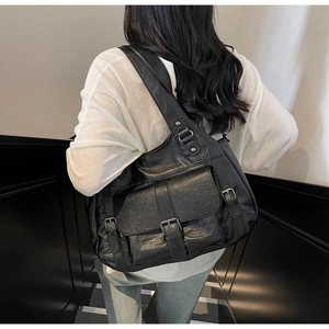 Detail of black vintage faux leather tote bag with functional metal buckle pocket