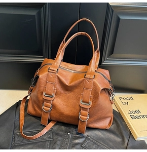Detailed view of brown large capacity tote bag with texture on dark leather jacket