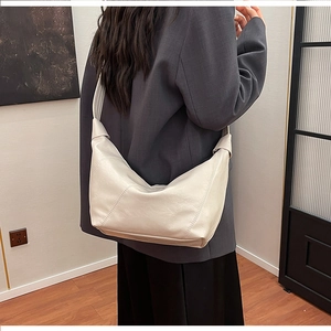 Chic cream dumpling bag with knot handle detail shown as a crossbody on model