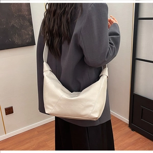 Rear view of model carrying a minimalist white crescent shoulder bag in soft leather