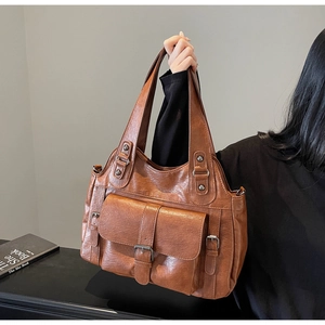 Detailed view of brown leather tote bag with large front pocket and retro buckle