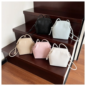 Detail of five pastel textured PU leather shell bags on wooden steps in a modern display