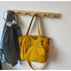 Detail of yellow nylon tote bag featuring front zipper pocket and round coin purse attachment