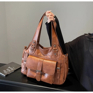 Close-up of brown PU leather tote bag featuring front flap pocket and vintage metal buckle