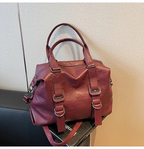 Detail view of the deep red faux leather tote bag with dual handles and silver buckles