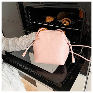 Close-up of pink lychee texture bucket bag held by a model in a creative studio setting