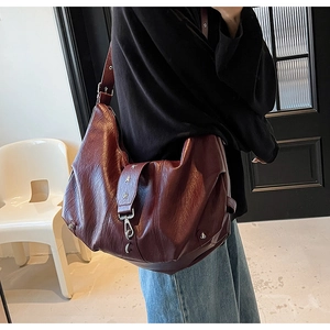 Detail of burgundy vintage leather tote featuring star rivets and silver metal hook buckle