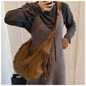 Detailed close-up of bohemian brown suede shoulder bag with retro fringe and adjustable strap