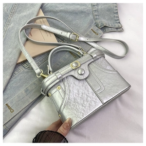 Detail of silver metallic handbag with unique pocket stitching and deconstructed design