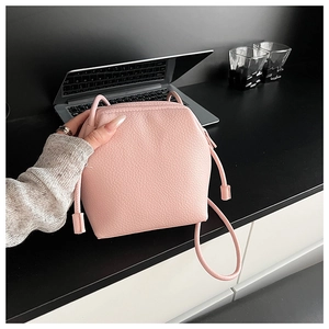 Detailed view of pink drawstring bucket bag with premium lychee grain leather texture