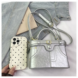 Silver metallic mini denim box bag shown next to a smartphone for size comparison