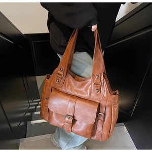 Close-up of brown vintage faux leather tote bag with metal buckle and soft texture