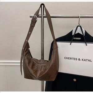 Detail of a dark brown PU leather dumpling bag with silver hardware and adjustable strap