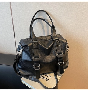 Detail of the black leather Boston bag with silver metal buckles and reinforced handles