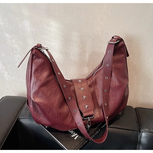 Close-up of wine red leather tote with silver star rivets and metallic eyelets on strap