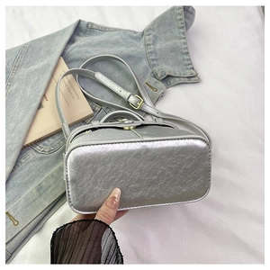 Close-up of silver metallic leather handbag with embossed texture on denim jacket