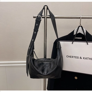 Detailed shot of a black hobo bag with adjustable silver grommet strap on a hanger
