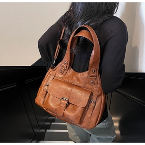 Detailed view of a retro brown leather tote bag with functional buckle pocket for daily use