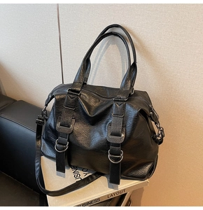 Close-up of black leather tote bag showing textured PU finish and silver metal buckle